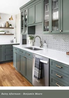 a kitchen with green cabinets and white counter tops, wood flooring and stainless steel appliances