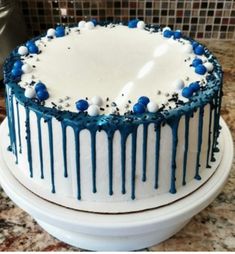 a blue and white cake with sprinkles on it sitting on a counter