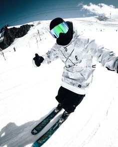 a man riding skis down the side of a snow covered slope with his hands in the air