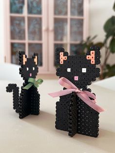 two black cats made out of legos sitting next to each other on a table