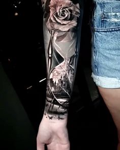 a person with a tattoo on their arm holding a rose in the middle of his arm