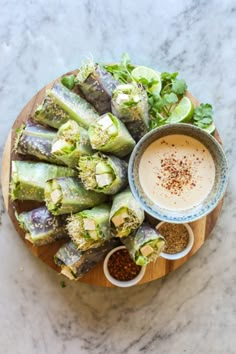 an overhead view of vegetables and dipping sauce on a wooden platter with a bowl of seasoning