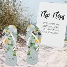 a pair of flip flops sitting in the sand next to a sign that says flip flops