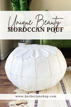 a large white pouf sitting on top of a wooden floor next to a plant