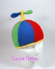 a crochet hat with a dragon on top is shown in red, green, blue and yellow