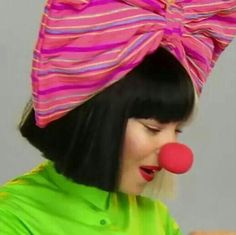 a woman with black hair wearing a pink and red clown hat