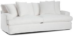 a white couch with four pillows on it's back and one arm facing the camera