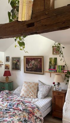 a bed sitting under a wooden beam in a bedroom next to a wall with pictures on it