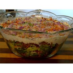 a large glass bowl filled with salad on top of a wooden table