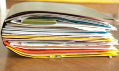 a stack of papers sitting on top of a wooden table