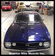 an old muscle car is parked in a garage with other cars behind it and the words quarter mile muscle inc written on the front