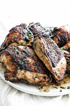 grilled chicken on a white plate with parsley sprinkled around the edges