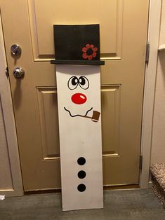 a door hanger with a snowman face painted on it