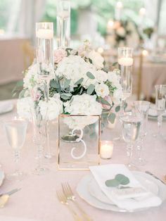 the table is set with white flowers and candles for an elegant wedding breakfast or reception