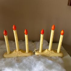 four yellow candles with orange tops are sitting on some white fur