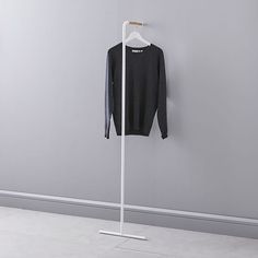 a black sweater hanging on a white coat rack