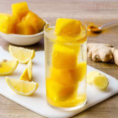 a glass filled with lemonade sitting on top of a cutting board next to sliced lemons