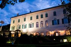 a large white building with green shutters and lights on it's windows at night