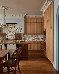 a large kitchen with wooden floors and cabinets in the center, along with a dining room table set for four