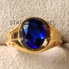 a gold ring with a blue stone in the center on a white cloth covered surface