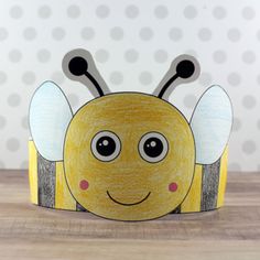 a paper crown with a yellow bee on it's head and two black eyes