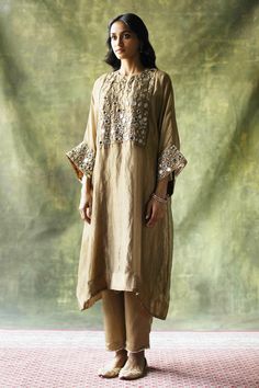 Beige zari silk kaftan kurta embellished with mirror work across the yoke and sleeves. Come with pants with mirror finished trims and a slip.
Component: 3
Pattern: Embroidery
Type Of Work: Mirror work
Neckline: Round
Sleeve Type: Loose sleeves
Fabric: Kurta: Zari Silk, Slip: Satin, Pant: Modal Satin
Color: Beige
Other Details: 
Mirror work
Zari silk kurta
Occasion: Mehendi and Haldi - Aza Fashions Kaftan Set, Kaftan Kurta, Western Dresses For Women, Kaftan Designs, Silk Kurta, Silk Kaftan, Satin Pants, Fancy Dress Design, Satin Color