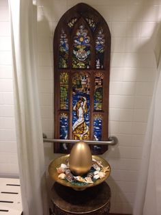 an ornate stained glass window in the corner of a bathroom with a gold bowl on it