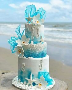 a blue and white wedding cake on the beach