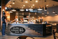 the interior of a coffee shop with people standing at the counter