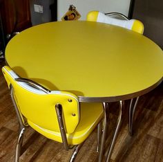 a yellow table with four chairs around it on a hard wood floored flooring