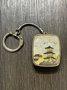 a keychain with a painting on it sitting on top of a wooden table