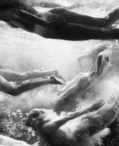 three people swimming in the water with their backs to each other