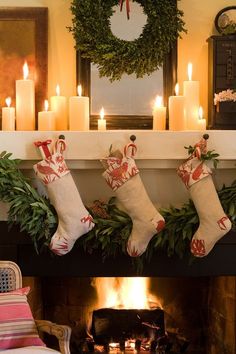 christmas stockings hung over a fireplace with lit candles