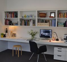 a desk with a computer on top of it in front of some bookshelves