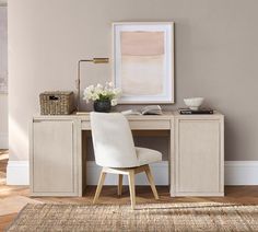 a white chair sitting in front of a desk with a painting on the wall behind it