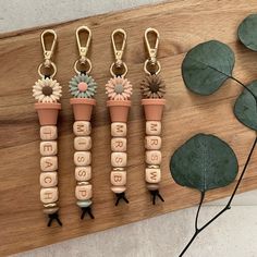 four wooden pegs with flowers and words on them sitting next to a leafy green plant