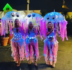 three girls dressed in costumes with lights on their heads and hands, standing next to each other