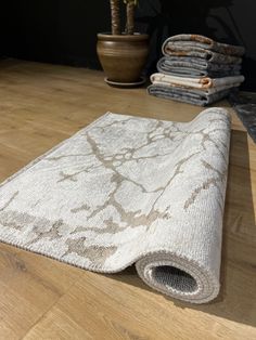 a pile of towels sitting on top of a wooden floor next to a potted plant