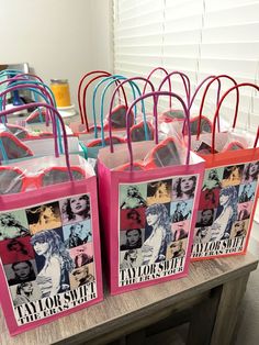 pink and blue shopping bags with photos of taylor swift on them sitting on a table