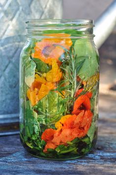 a jar filled with flowers sitting on top of a wooden table