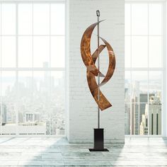 an abstract sculpture stands in the middle of a room with large windows and cityscape