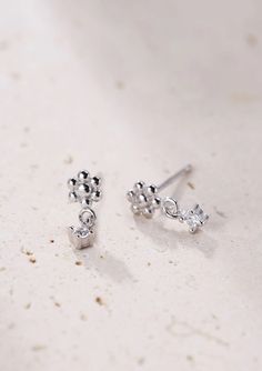 Made from solid 925 sterling silver, these are small stud earrings that have a delicate metallic flower with six 'petals' that sits on the ear lobe, a tiny square zirconia hanging underneath and silver butterfly clasps. Compact, with a timeless design, these studs will pair well with other delicate hoops or studs. 🎁 Packaging: Beautifully packed in a box, ready for gifting. 🏷️ This product is made of sterling silver -- easily recognizable by its '925' stamp of authenticity. It is also hypoallergenic, making it suitable for people with sensitive or irritable skin. We recommend avoiding perfume, deodorant or other chemicals. Details: ✅ Material: 925 sterling silver with 18k gold plated, cubic zirconia ✅ Available in gold and silver ➕ Purchase extra earring backs to make sure your favorite Tiny Silver Cubic Zirconia Earrings, Silver Minimalist Dangle Flower Earrings, Delicate Silver Flower Earrings With Cubic Zirconia, Silver Dangle Flower Earrings Minimalist Style, Delicate Silver Cubic Zirconia Flower Earrings, Dainty Silver Flower Charm Earrings, Tiny Sterling Silver Flower Earrings, Silver Dainty Dangle Flower Earrings, Tiny Silver Flower Earrings