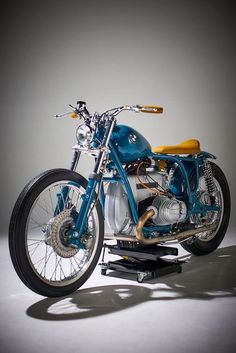 a blue motorcycle parked on top of a white floor next to a gray wall in the background