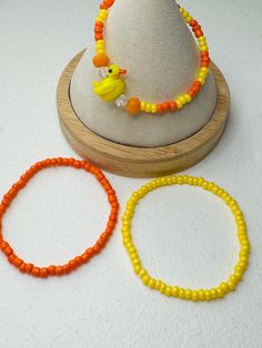 three bracelets and a hat on a white table with a wooden stand holding two necklaces