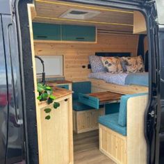 the interior of a van with its door open to reveal a bed and desk area