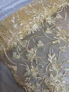 an embroidered fabric with gold flowers and leaves on grey background, closeup view from the bottom