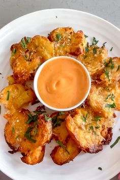 a white plate topped with fried potatoes and dipping sauce