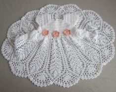 a white doily with pink flowers on it sitting on top of a gray surface