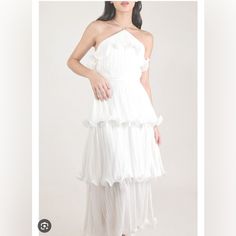 a woman is wearing a white dress with ruffles