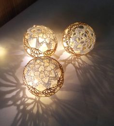 three decorative lights sitting on top of a white countertop next to a shadow cast wall